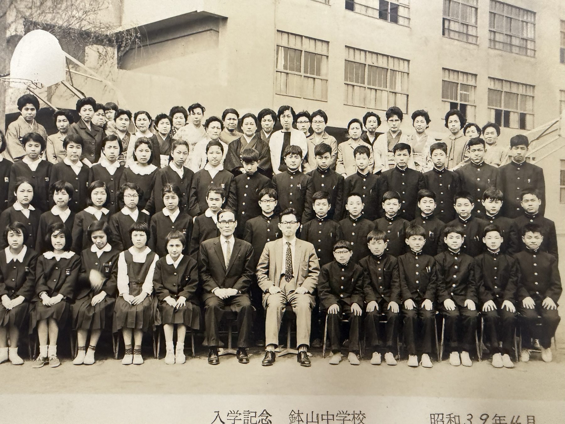 鉢山中学校の校舎前に並ぶ生徒と教職員の入学記念写真