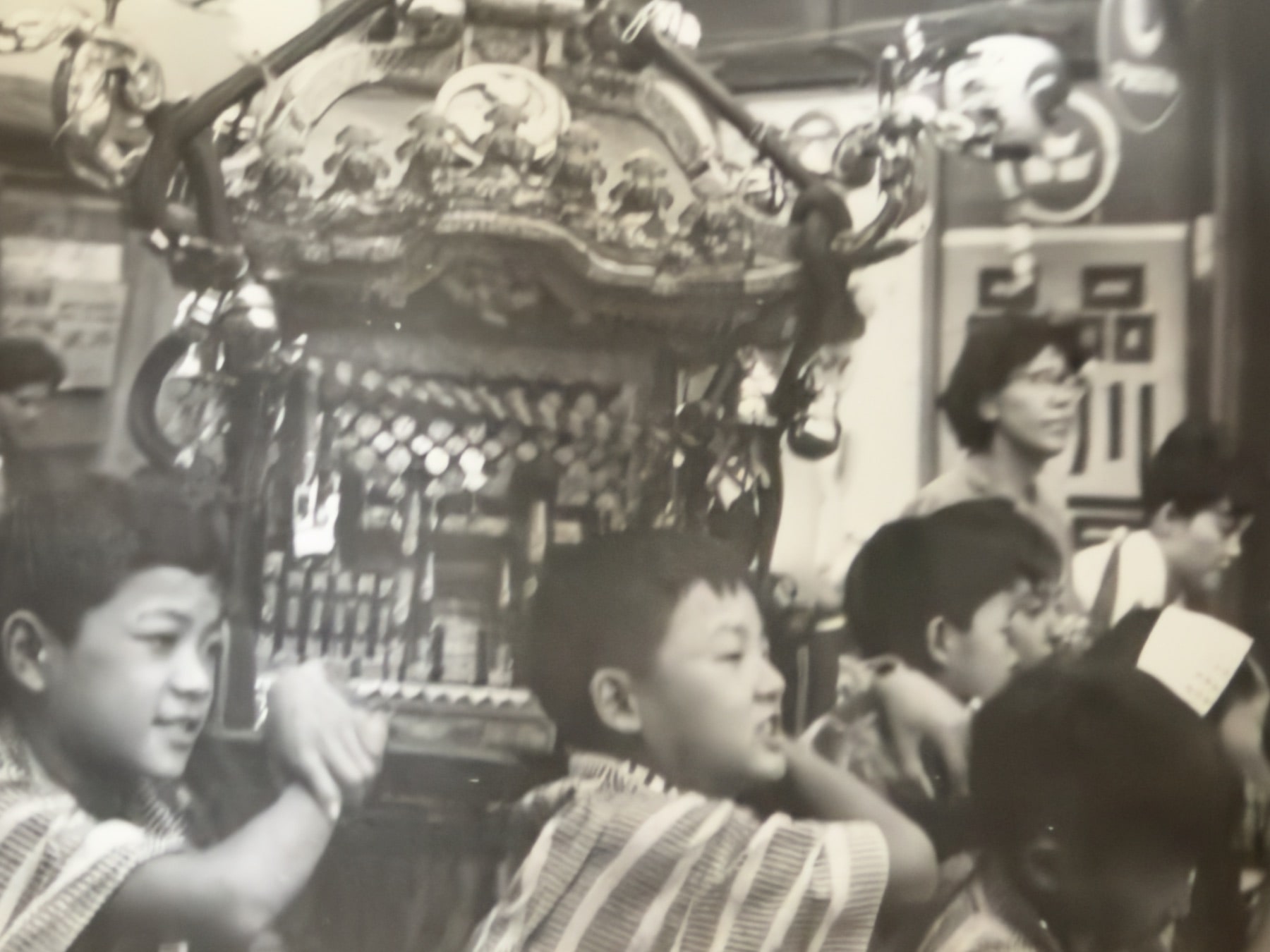 神輿のそばで法被姿の人々と子どもが集う様子