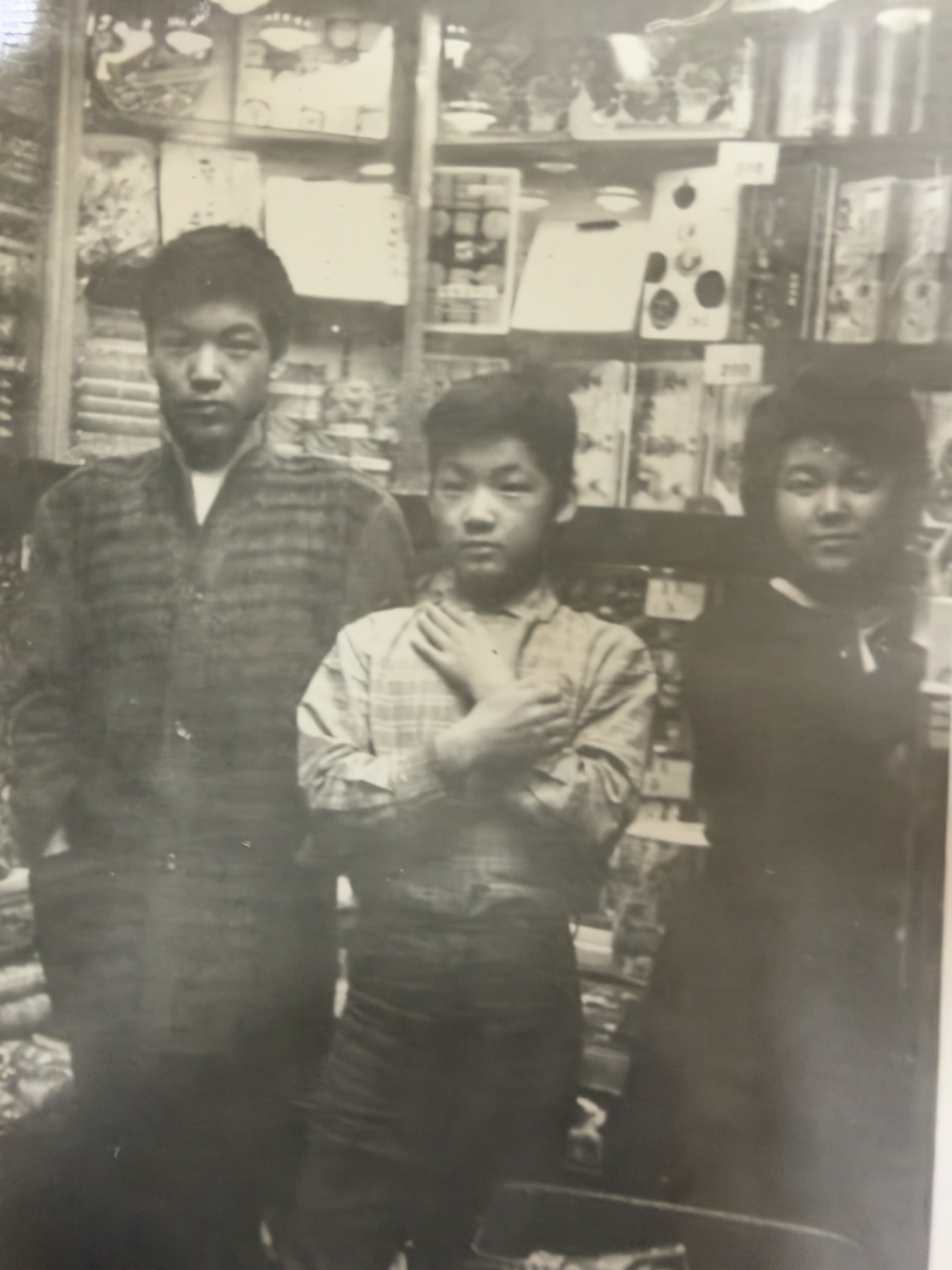 箱や袋入りの商品が並ぶ棚の前に立つ3人